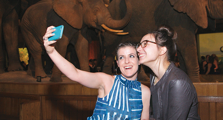 Students taking a selfie in front of wolly mammoths at the American Museum of Natural History