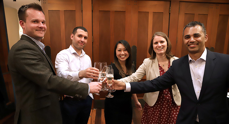 Graduating members of the first Masters in Cybersecurity Risk and Strategy class celebrating with a champagne toast