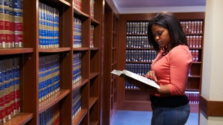 Student standing in library with a book