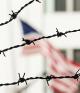 barbed wire in front of building with American flag in background