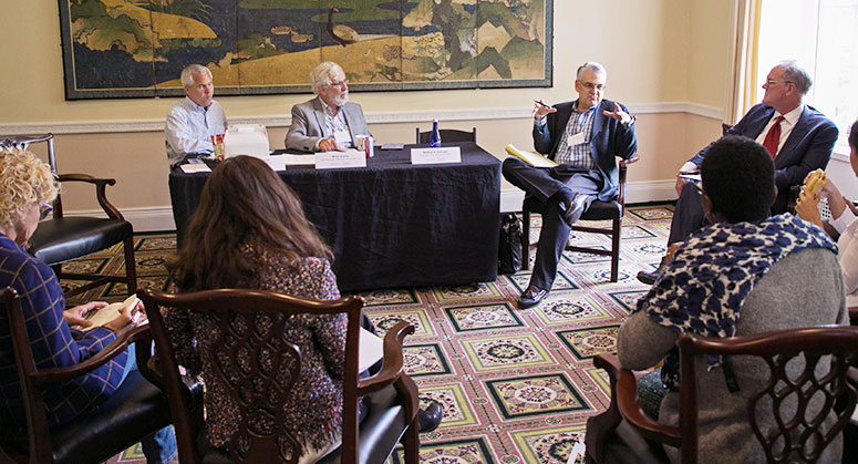 People sitting in a circle, listening to a panelist speak