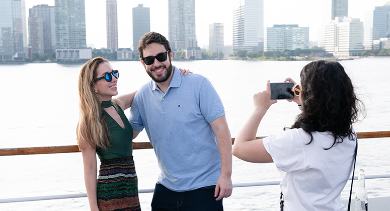 Student taking photo of another couple of students posed in front of city skyline