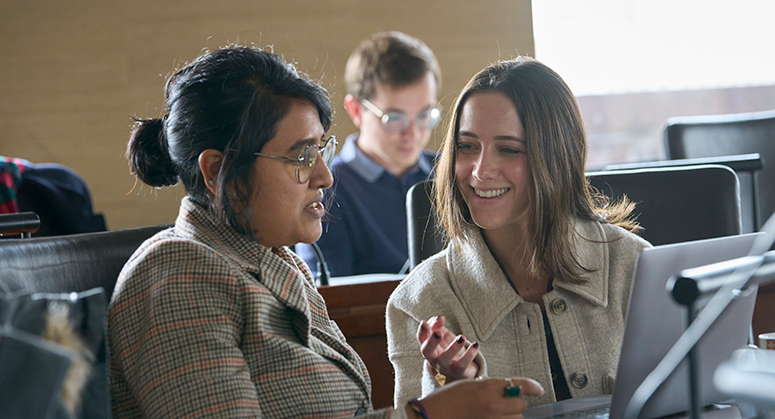 Two students in class speaking with one another