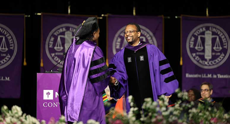 Dean Troy McKenzie shakes hands with a student at 2023 Convocation