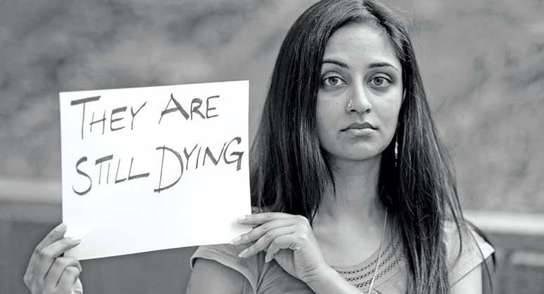 Priti Krishtel holding a sign that reads "They are still dying"