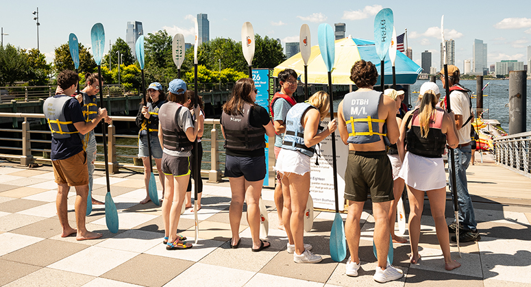 Students on dock with kayak paddles