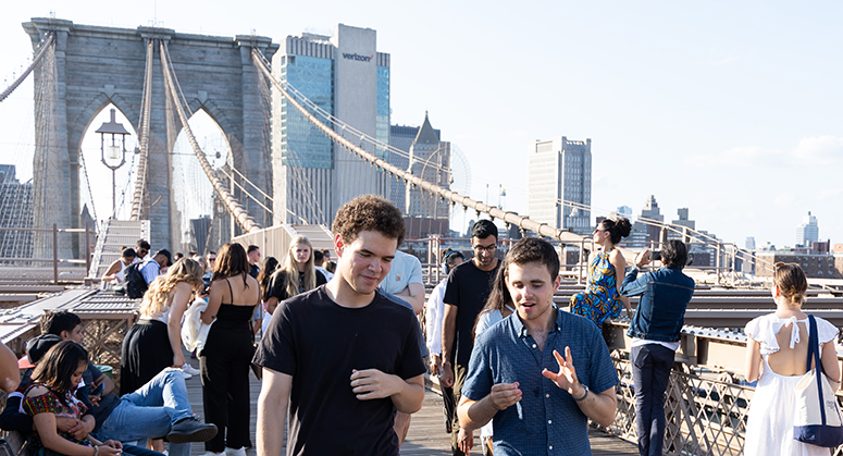 Two students talking as they cross the Brooklyn Bridge