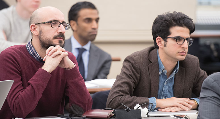 Two audience members listening intently to the panel