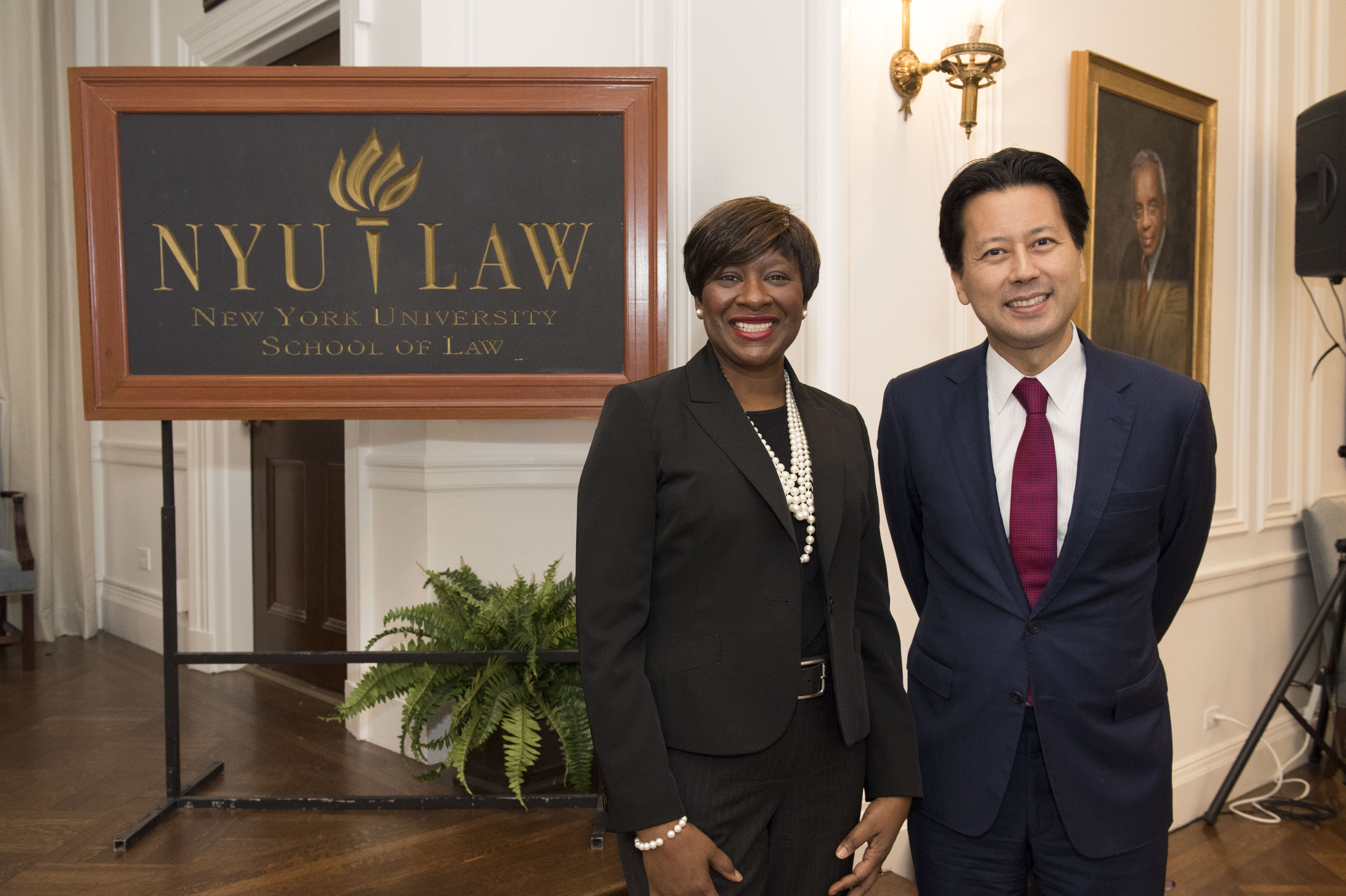 Professor Katherine Phillips and Professor Kenji Yoshino pose by the NYU Law sign