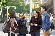 Four students talking on sidewalk in front of Vanderbilt Hall