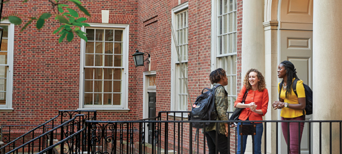 three women students talking on steps of Vanderbilt Hall courtyard