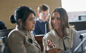 Two students in class speaking with one another