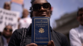 A person holding a copy of the Constitution of the United States of America.