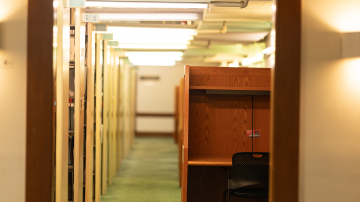 Walkway with tall bookshelves on the left and study carrels on the right