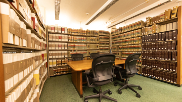 Table surrounded by four chairs and bookshelves