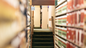 View through bookshelves to a staircase in the distance