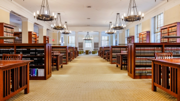 Walkway through a library with study tables and low bookshelves on either side