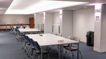 Several white tables surrounded by chairs