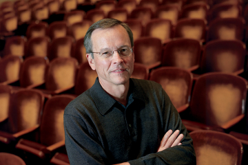 Frank Upham, arms folded, with theater seats in background