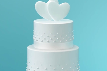 White wedding cake with hearts on top, in front of baby blue background