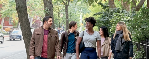 Five students walking down street next to campus