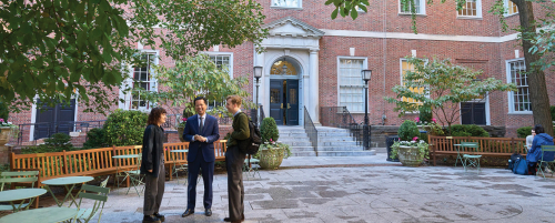 Three professors standing and talking in the courtyard