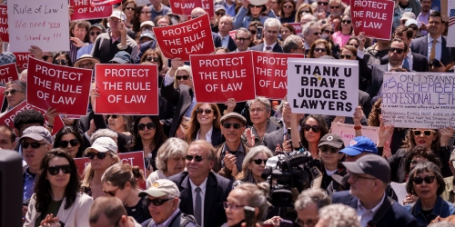 Group of protesters holding signage to protect the rule of law.