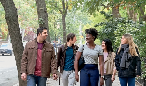 Five students walking down street next to campus