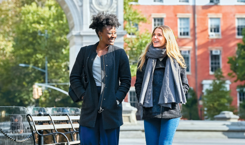 Two students walking together through Washington Square Park.