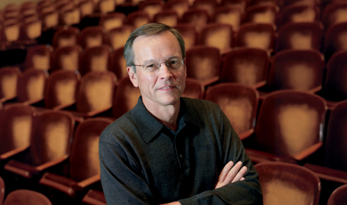 Frank Upham, arms folded, with theater seats in background