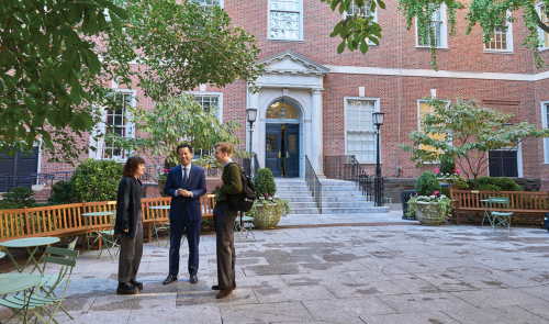 Three professors standing and talking in the courtyard