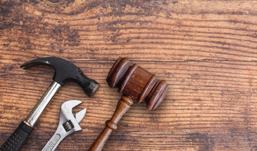 Hammer, wrench, and gavel on wooden surface