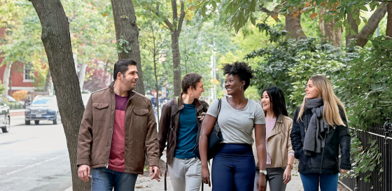 Five students walking down street next to campus
