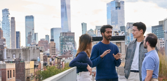 Students talking on balcony with skyline behind them