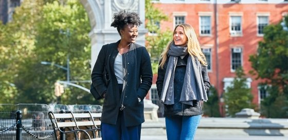 Two students walking together through Washington Square Park.