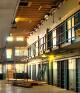 Interior of disused prison with sunlight striking empty cellblock