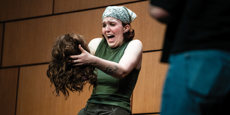 Student holds fake head onstage