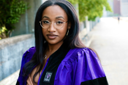 Headshot of Keiana James standing outside wearing her graduation gown. 