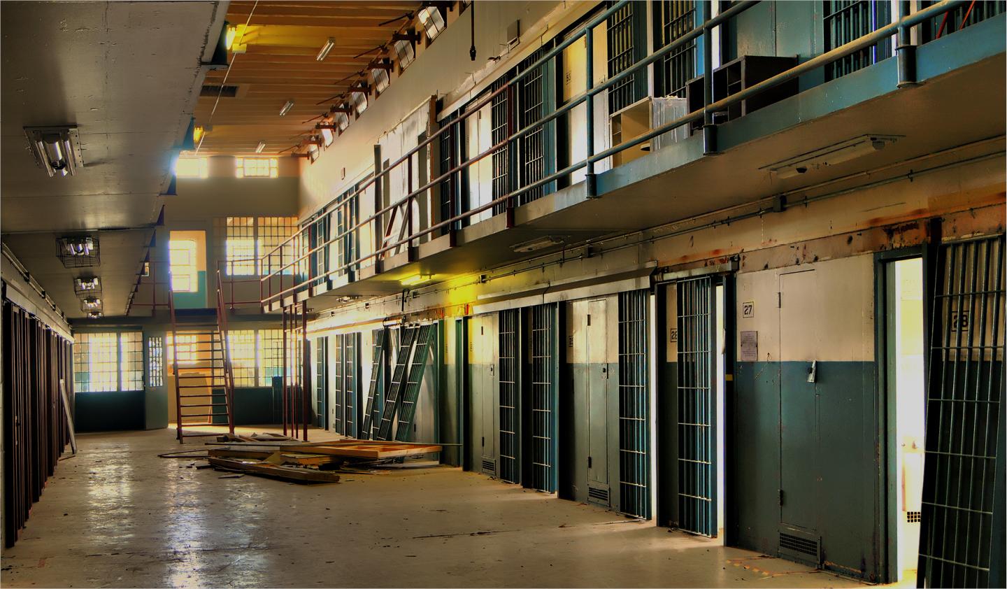 Interior of disused prison with sunlight hitting empty cellblock