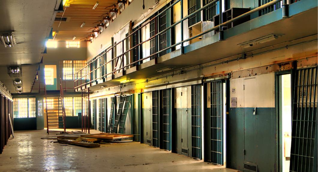 Interior of disused prison with sunlight striking empty cellblock