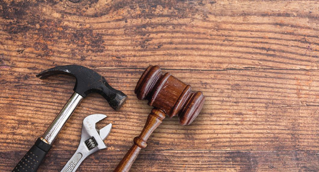 Hammer, wrench, and gavel on wooden surface