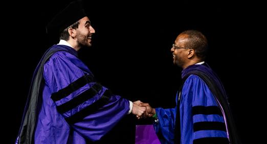 Dean Troy McKenzie shakes a graduate's hand at 2025 Convocation