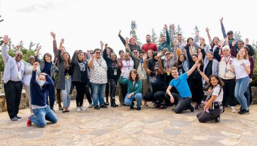 group of 50 people smiling and raising their arms together