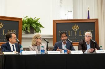 Three people sitting at table with microphones at NYU Law