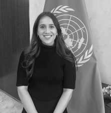 Woman with long hair smiling and standing in front of flag