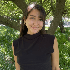 Woman with medium length dark hair smiling with trees in the background