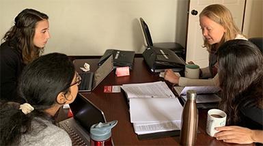 Students working on computers and writing at a desk