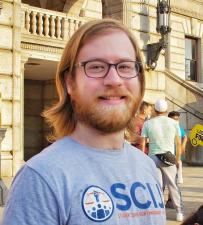 White man with shoulder-length blonde hair and facial hair smiling