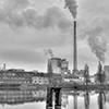 A black and white photo of an industrial building along a river.
