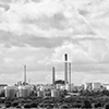 A black and white photo of an expansive industrial facility with smoke stacks and storage tanks.